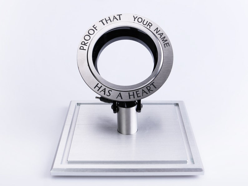 May include: A silver ring with the inscription "Proof that your name has a heart". The ring is on a silver stand.