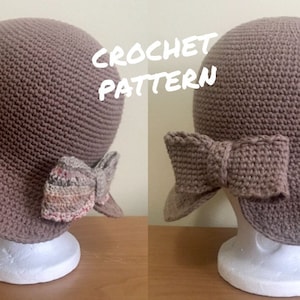 Puede incluir: Un sombrero de crochet marrón con un lazo de crochet marrón en el lateral. El sombrero está en una cabeza de maniquí blanca. El texto "CROCHET PATTERN" está escrito en blanco sobre fondo negro.