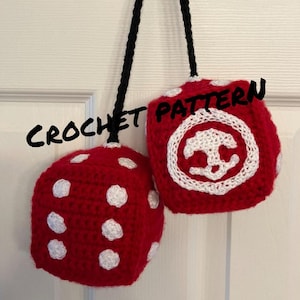 May include: Two crocheted dice, one red with white dots and one red with a white anchor symbol, hanging from a black cord. The dice are labelled "CROCHET PATTERN".