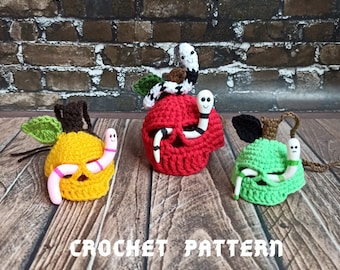 May include: Three crocheted apple ornaments with a worm peeking out of each. The apples are red, yellow, and green. The text "CROCHET PATTERN" is visible at the bottom of the image.