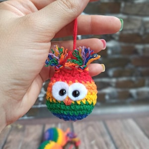 Peut inclure: Porte-clés hibou en crochet arc-en-ciel avec de grands yeux noirs. Le hibou est attaché à un anneau de clé en or.