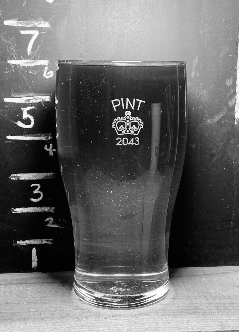 May include: A clear glass pint glass with a crown and the text "PINT 2043" etched on the side.