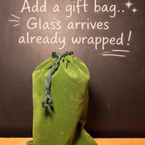 May include: A green velvet gift bag with a drawstring closure. The bag is on a dark background with the text "Add a gift bag... Glass arrives already wrapped!"
