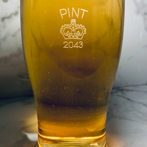 May include: A clear glass pint glass with the words "PINT 2043" etched on the side. A crown is etched above the text.