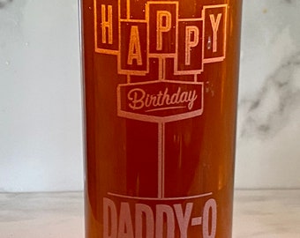 May include: A tall glass with a birthday message for "Daddy-O." The glass is filled with a dark amber liquid, topped with a foamy head. The words "HAPPY Birthday DADDY-O" are etched into the glass in a decorative font.