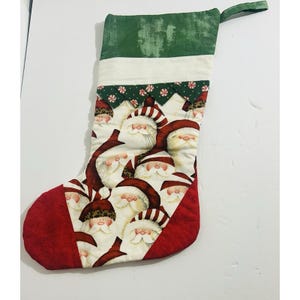 以下が含まれることがあります： 赤い爪先とかかと、サンタクロースの顔が描かれた白い中央部、緑色のトップが付いたクリスマスストッキング。吊り下げ用のループが付いており、生地で作られています。