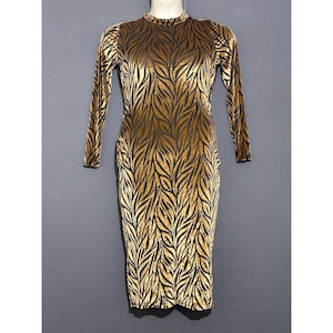 May include: A long-sleeved, knee-length dress with a high neckline. The dress has a pattern of black leaf-like shapes on a gold background. The fabric appears to be velvet, giving the dress a luxurious look. The dress is displayed on a mannequin.