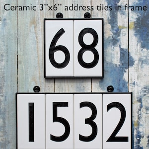 May include: Two sets of ceramic house numbers in black on white tiles with a black frame. The top set reads "68" and the bottom set reads "1532".