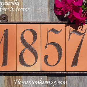 May include: Terracotta house number sign with the numbers 1857 in a dark brown font. The sign is in a dark brown metal frame. The text "Terracotta 4 numbers in frame" is at the top. The website address is at the bottom.