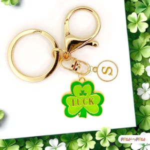 May include: Gold keyring with a green shamrock charm that says "LUCK" and a white charm with the letter "S".