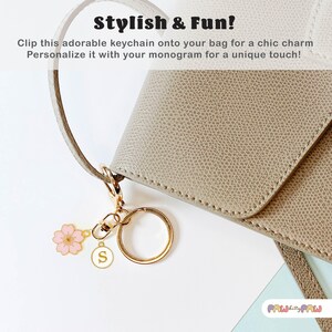 Pink enamel Sakura cherry blossom keychain with gold outline, attached to a gold keyring and an initial charm