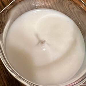 May include: A close-up of a white, creamy substance in a clear glass bowl. The substance has a swirling pattern in the center.