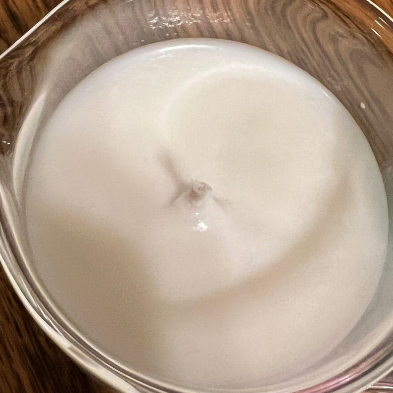 May include: A close-up of a white, creamy substance in a clear glass bowl. The substance has a swirling pattern in the center.