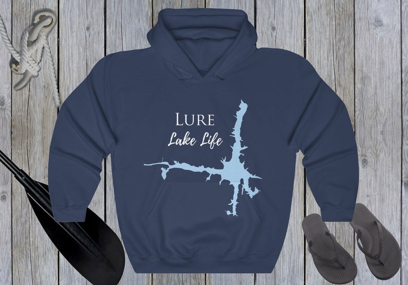 Op de afbeelding: Donkerblauwe hoodie met een witte omtrek van een meer en de tekst "LURE Lake Life" gedrukt op de voorkant.