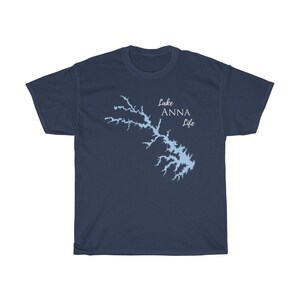 Op de afbeelding: Een marineblauw t-shirt met een lichtblauwe omtrek van Lake Anna en de tekst "Lake Anna Life" in wit.