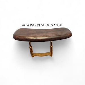 May include: A dark brown violin shoulder rest with gold-coloured metal hardware. The text "ROSEWOOD GOLD U CLUM" is printed above the rest. The rest is designed to provide comfort and support while playing the violin.