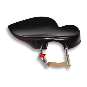 Puede incluir: Un apoyo para el hombro de violín negro con forma curvada. El reposahombros tiene una superficie acolchada y se sujeta con clips metálicos con detalles rojos y plateados. Una almohadilla de corcho está unida a los clips.