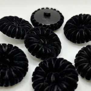 Peut inclure: Sept boutons en velours noir avec un motif circulaire en relief. Les boutons ont un diamètre d'environ 2,5 cm.