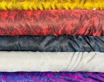 May include: A stack of fabric rolls with paisley patterns in various colours, including orange, grey, yellow, red, black, white, purple, and brown.