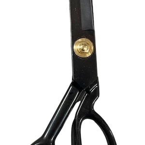 Könnte beinhalten: Schwarze Stoffschere mit einer goldenen Schraube. Die Schere hat eine lange, spitze Klinge und einen komfortablen Griff.