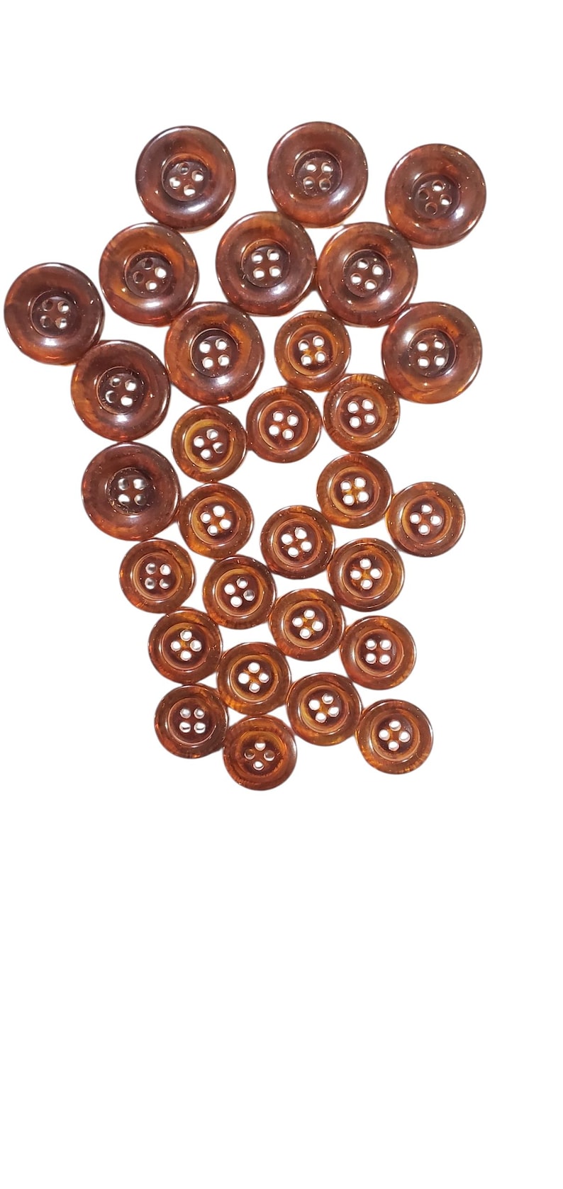 May include: A selection of brown buttons in different sizes, set against a white backdrop. The buttons have a glossy finish and four holes for sewing. The buttons are made of a hard, durable material.