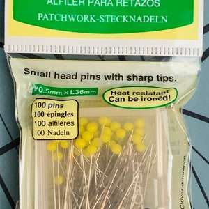 May include: A pack of 100 small head patchwork pins with yellow and blue coloured heads. The pins are heat resistant and can be ironed. The pack is labelled "Clover Patchwork Pins" and includes the text "0.5mm x L36mm".