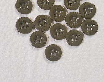 Peut inclure: Ensemble de boutons vert olive à quatre trous chacun. Les boutons sont ronds et légèrement brillants. Ils sont dispersés sur une surface blanche et texturée.
