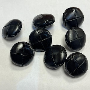 May include: Eight black leather buttons with a woven design. The buttons are round and have a slightly raised centre.