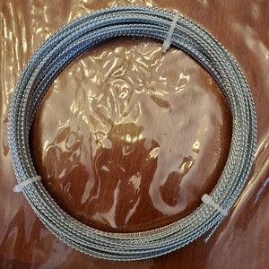 May include: A silver braided wire coil, likely used for crafts or jewelry making.