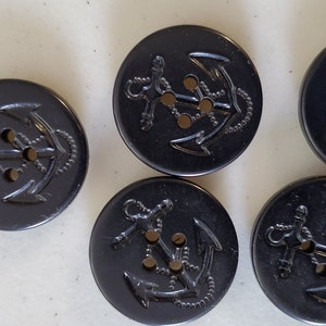 May include: Five black plastic buttons with an anchor design. Each button has three holes.