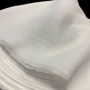 May include: A stack of white gauze fabric, folded and ready for use. The fabric is soft and lightweight, making it ideal for a variety of purposes.