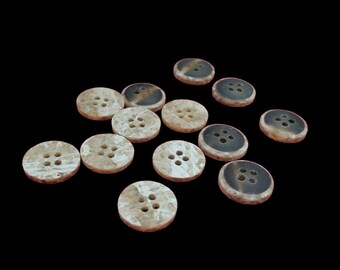 Könnte beinhalten: Eine Ansammlung von dreizehn runden Knöpfen mit einem Marmormuster in Beige-, Creme- und Dunkelbrauntönen. Jeder Knopf hat vier Löcher in der Mitte und einen glatten, kreisförmigen Rand, der eine Mischung aus hellen und dunklen Farbvariationen aufweist.
