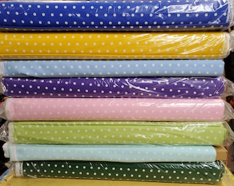 May include: A stack of eight rolls of fabric with white polka dots on different coloured backgrounds. The colours are blue, yellow, light blue, purple, pink, green, light blue, and green.