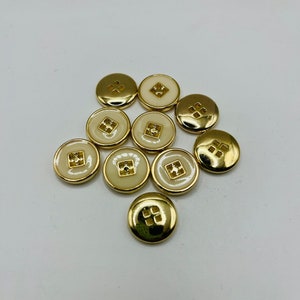 Peut inclure: Un groupe de dix boutons dor&eacute;s avec un centre blanc. Les boutons ont un motif carr&eacute; au centre.