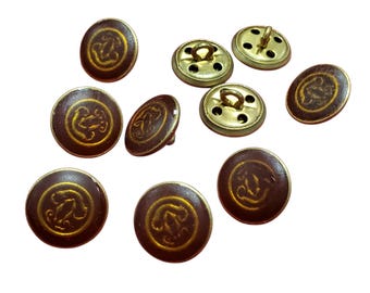 Könnte beinhalten: Eine Ansammlung von neun runden Knöpfen mit einer dunkelbraunen Oberfläche und einem goldenen, geprägten Emblem in der Mitte. Einige Knöpfe zeigen die glatte, dunkelbraune Vorderseite, während andere die goldfarbene Metallrückseite zeigen.