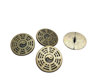 Könnte beinhalten: Vier runde Metallknöpfe mit antikem Messing-Finish. Drei Knöpfe zeigen ein zentrales Yin-Yang-Symbol, umgeben von einem kreisförmigen Muster aus Trigrammen. Ein Knopf ist von der Rückseite zu sehen und zeigt eine glatte Fläche mit Öse.