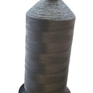 以下が含まれることがあります： 縫製やクラフトプロジェクトに適した、濃い灰色の糸の糸巻き。 糸は円筒形のコアにしっかりと巻き付けられており、黒いベースと上部が付いています。 糸は耐久性のある素材で作られているようです。