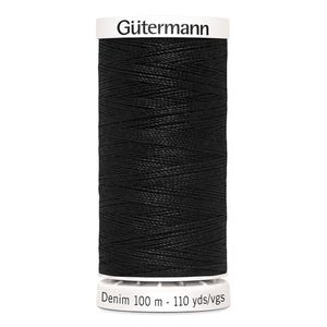 Puede incluir: Una bobina de hilo negro Gütermann Denim. La parte superior e inferior blancas de la bobina muestran el logotipo de Gütermann y la información del producto. El hilo está bien enrollado, lo que sugiere un material fuerte y duradero para el denim.