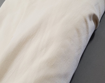 May include: A folded piece of off-white fabric on a gray surface.