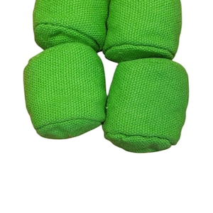 Peut inclure: Quatre articles cylindriques en tissu vert vif sont disposés en carré sur fond blanc. Les articles ont un aspect texturé et tissé, et sont éclairés uniformément, mettant en valeur leur couleur vive.