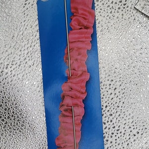 May include: A blue and white package with the text "Prym Wendenadel Loop turn" and a silver loop turner tool with a pink fabric loop threaded through it.