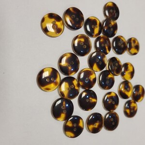 May include: A collection of brown and yellow tortoiseshell buttons with two holes each.