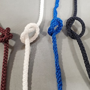 May include: Five different colours of braided rope with knots tied in them. The ropes are black, maroon, white, blue, and dark grey.