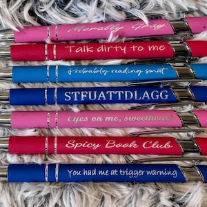 Pu&ograve; includere: Un set di dieci penne con corpi di diversi colori e dettagli argentati. Ogni penna ha un messaggio inciso diverso, tra cui "Morally Gray", "Talk dirty to me", "Probably reading smut", "STFUATTDLAGG", "Eyes on me, sweetheart", "Spicy Book Club" e "You had me at trigger warning".