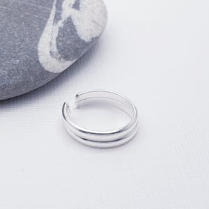 May include: A silver toe ring with a double band design.