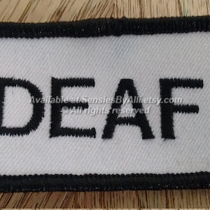 May include: White rectangular patch with black border and the word "DEAF" embroidered in black.