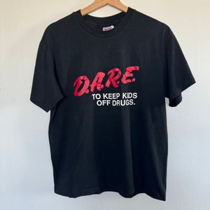 May include: Black t-shirt with a red graphic that says "DARE TO KEEP KIDS OFF DRUGS."