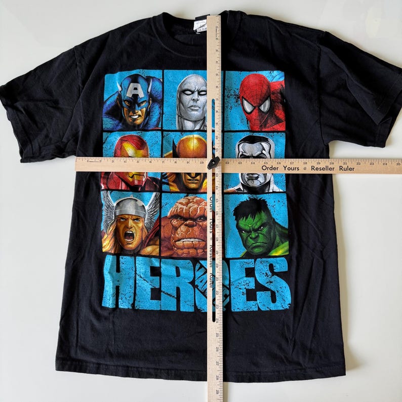 May include: Black t-shirt featuring a grid of Marvel comic book heroes, including Captain America, Spider-Man, and the Hulk. The word "HEROES" is printed in large, blue, distressed letters across the bottom of the shirt.