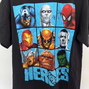 May include: Black t-shirt featuring a grid of Marvel superhero portraits, including Captain America, Spider-Man, and Iron Man. The word "HEROES" is printed in blue, with the Marvel logo below.