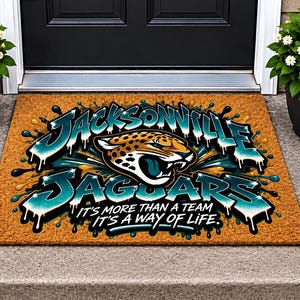 May include: A rectangular tan coir doormat featuring a graphic of a jaguar head and the text Jacksonville Jaguars. Below the team name, the text reads It's more than a team it's a way of life. The design includes teal and gold paint splatter effects.